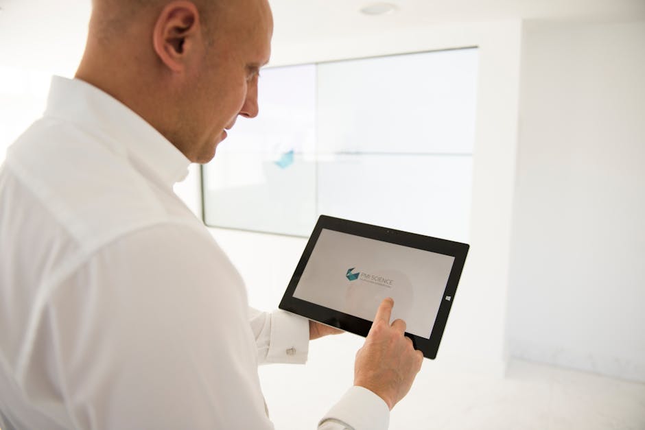 A well-dressed businessman uses a tablet inside a modern office environment.